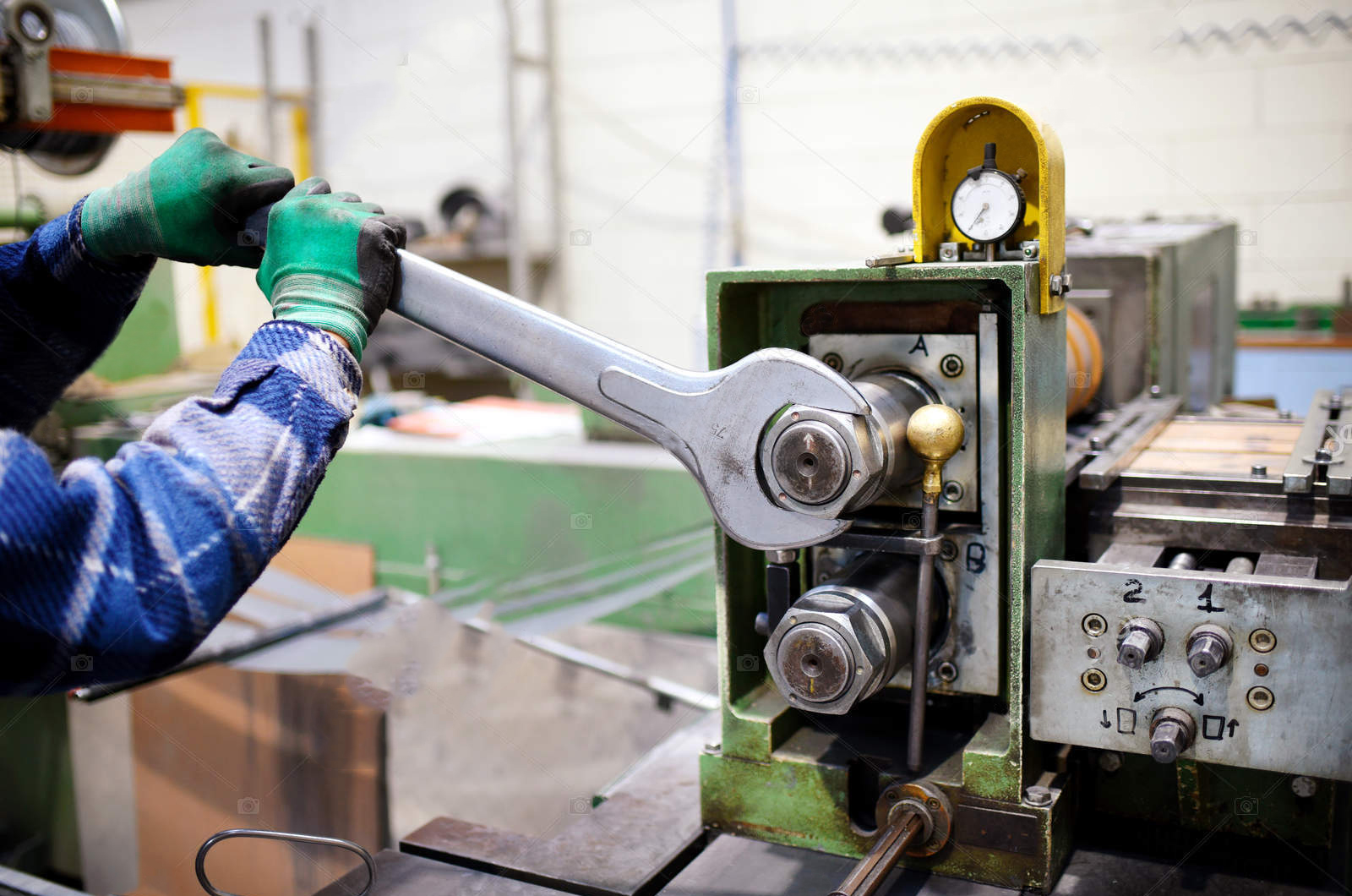 worker adjusting machinery with large wrench